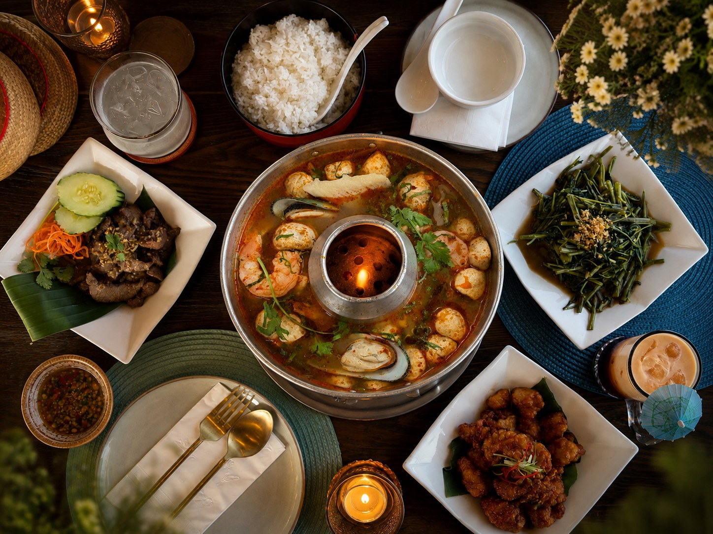 A family-style Thai spread at Narwhal Thai Table — wonton soup, crying tiger, orange chicken and morning glory